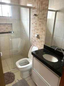 a bathroom with a toilet and a sink and a shower at Hospedagem Vermont in Maringá +5 photos