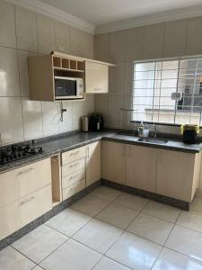 a kitchen with white cabinets and a microwave at Hospedagem Vermont in Maringá