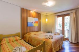 a hotel room with two beds and a balcony at Pousada Joia da Serra by Hotel Platanus in Campos do Jordão