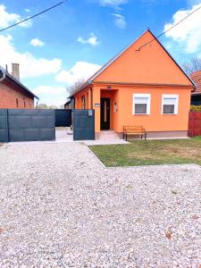 una casa naranja con un banco delante en Apartman Lipa- Lipovac Bajakovo, en Lipovac