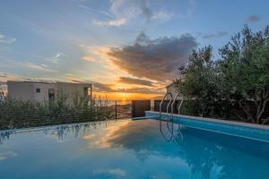 ein Swimmingpool mit einem Sonnenuntergang im Hintergrund in der Unterkunft Villa Spectra in Makarska