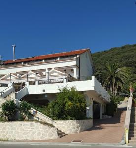 a large white building with stairs and palm trees at Guest House Galeb in Supetarska Draga
