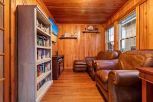 een woonkamer met lederen meubels en boekenplanken bij Danemead Cottage - For 10ppl in Old Orchard Beach