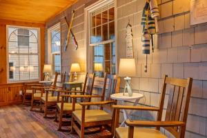 een restaurant met houten stoelen en tafels en ramen bij Danemead Cottage - For 10ppl in Old Orchard Beach