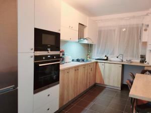 eine Küche mit weißen Schränken und einem schwarzen Backofen in der Unterkunft Double rooms apartament in Sînpetru