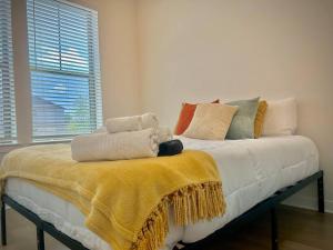 a bed with a yellow blanket on top of it at Modern&Cozy Washer Dryer Pool Gym WorkerFriendly in Sherman