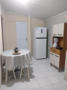 塞古罗港Pe no Centro的厨房里有一张桌子和一台白色冰箱