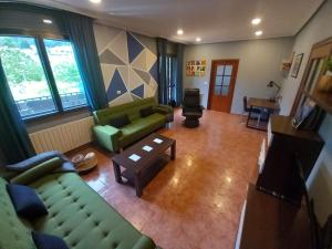 a living room with two green couches and a table at Casa Charo Prexigueiro in Ribadavia