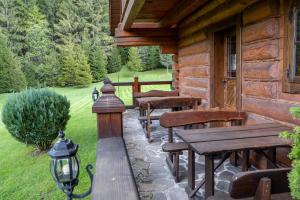 a porch of a log cabin with wooden tables and benches at Zrub Raj in Liptovský Ján
