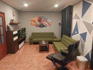 a living room with two green couches and a table at Casa Charo Prexigueiro in Ribadavia