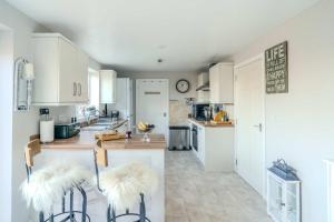 伊夫舍姆Modern 3-Bed in Historic Evesham & Garden的厨房配有白色橱柜和带2把椅子的柜台。