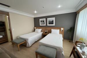 a hotel room with two beds and a chair at Mediterrâneo Flat in Rio de Janeiro