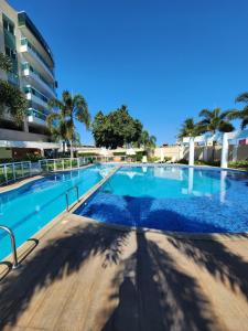 a swimming pool with blue water and palm trees at PACIFIC - PRAIA DO FORTE in Cabo Frio