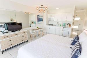 a white bedroom with a large bed and a kitchen at Waikiki Shore 1014 in Honolulu