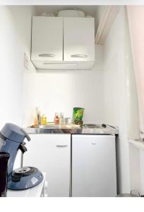 a small kitchen with white cabinets and a sink at Studio des Trois Frontières in Saint-Louis