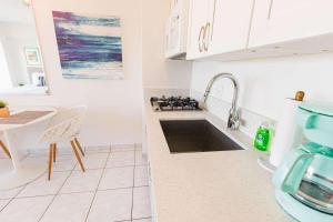 a white kitchen with a sink and a stove at Waikiki Shore 1014 in Honolulu +11 photos