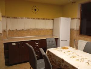 Una cocina con mesa y sillas y un refrigerador. en Central Rooms Craiova, en Craiova