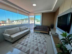 a living room with a couch and a flat screen tv at Vieques in Bombinhas