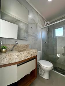 a bathroom with a toilet and a sink and a shower at Vieques in Bombinhas