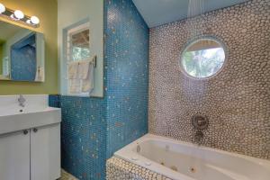 a bathroom with a tub and a sink and a mirror at Balinese Beach House With Pool in Pahoa +65 photos