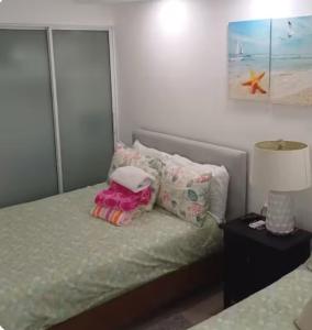 ein Schlafzimmer mit einem Bett mit Kissen und einer Lampe in der Unterkunft Oasis by the beach Retiro 1 in Punta Cana