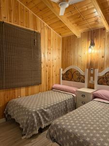 zwei Betten in einem Zimmer mit Holzwänden in der Unterkunft Casa Rural Los Peralejos Piscina Privada en Cazorla in Cazorla