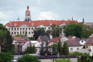 a large building with a clock tower in a city at Hotel Kreta in Kutná Hora