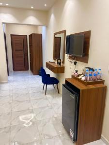 a living room with a television and a blue chair at Glamour Pyramids BoutiQue Hotel in Cairo