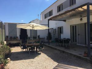 um pátio com uma mesa e guarda-chuva em frente a uma casa em Casa Rural Nacimiento del Hueznar - Tomillo 17 em San Nicolás del Puerto