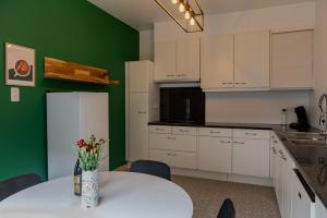 a kitchen with a white table and a green wall at Sur la Colline in Houffalize