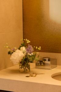 Un jarrón de flores en un mostrador en el baño en Hôtel D'Aubusson, en París 20 fotos más