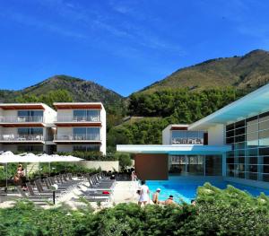 un hôtel avec une piscine avec des montagnes en arrière-plan dans l'établissement Sporting Club Resort, à Praia a Mare