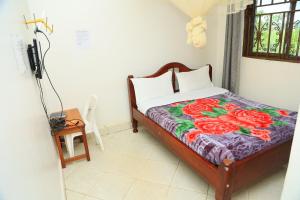 una camera da letto con un letto con una coperta floreale sopra di Little Flowers Motel a Fort Portal