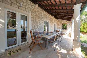 a patio with a table and chairs on a stone wall at Holiday Home Fiola in Zubovići