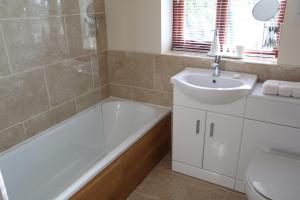 a bathroom with a tub and a sink and a toilet at Woodside Cottages - Beech cottage - Self-catering in Fletching +8 photos