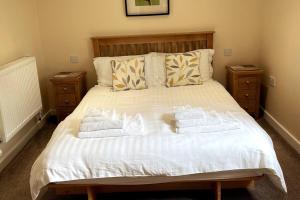 a bedroom with a bed with towels on it at Woodside Cottages - Beech cottage - Self-catering in Fletching