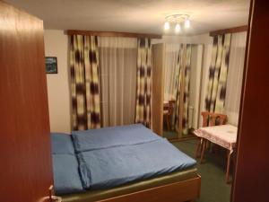 a small bedroom with a blue bed and a table at Haus Schiestl in Zell am Ziller