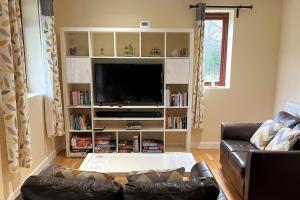 a living room with a couch and a flat screen tv at Woodside Cottages - Beech cottage - Self-catering in Fletching