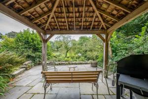 a wooden pergola with a table and chairs on a patio at Melin-Dwyfor in Criccieth
