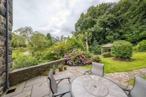 a patio with a table and chairs and flowers at Melin-Dwyfor in Criccieth