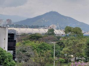 a large building with a mountain in the background at Hotel Stadio Cali in Cali