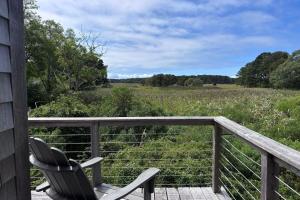 a deck with a chair and a view of a field at Wellfleet Vacation Townhome with Direct Marsh Views & Spa in Wellfleet