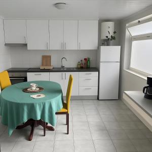 a kitchen with a table and chairs and a kitchen with white cabinets at Tiny apartment near the airport in Ponta Delgada