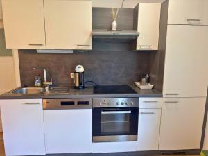 a kitchen with white cabinets and a stove top oven at Salzkammergut Homes Gmunden - Haus im Grünen, Ruhe, großer eingezäunter Garten - ideal für Familien und Hunde in Pinsdorf