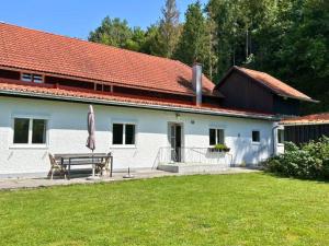 a white house with a bench and an umbrella at Salzkammergut Homes Gmunden - Haus im Grünen, Ruhe, großer eingezäunter Garten - ideal für Familien und Hunde in Pinsdorf