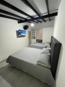 a bedroom with two beds and a tv on the wall at Hotel boutique Olaya 54 in Medellín