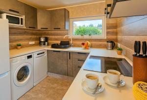 a kitchen with a washing machine and two cups of coffee at Otepää Holiday House with Sauna, Tehvandi Ski Jump View in Otepää