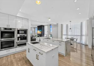 a large kitchen with white cabinets and a table at High-end Coastal Escape in Sunny Isles Beach