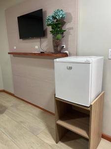 a small white refrigerator in a room with a tv at Pousada Bella Pantano in Pântano Grande