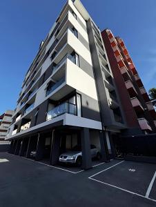 an apartment building with a car parked in a parking lot at Edificio EIFER V a 200 metros de la Av San Bernardo y a 200 metros del Mar con Aire Acondicionado Cochera Cubierta Balcón a la calle Parrilla y Lavadero in San Bernardo